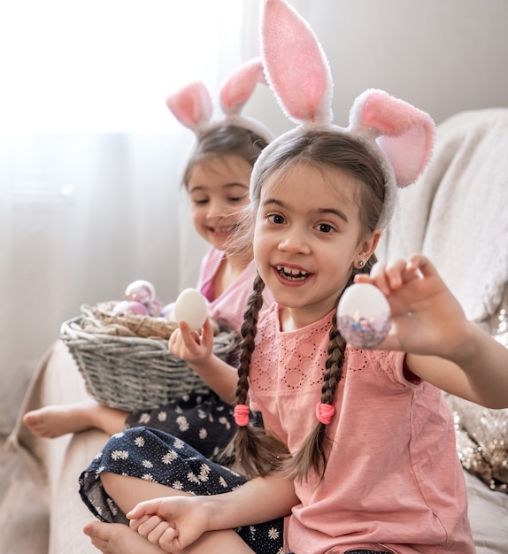 Little sisters with bunny ears posing with Easter eggs
