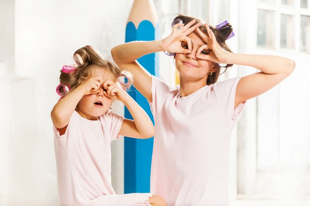 Little smiling girl playing with her mother on white