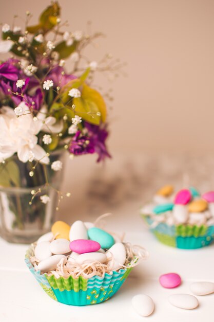 Little stones in baskets near vase with flower bouquet