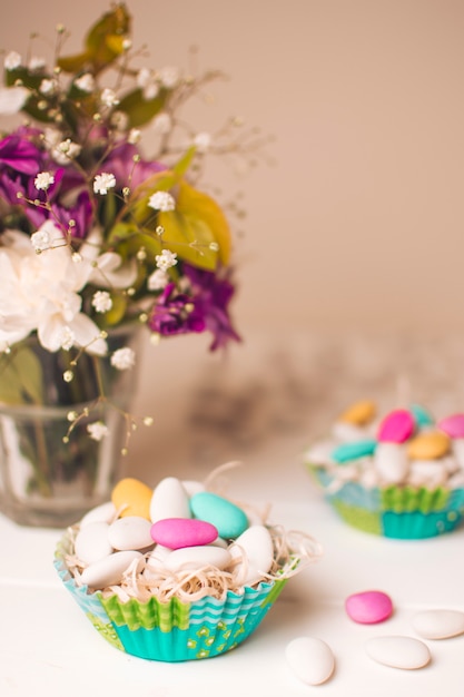 Little stones in baskets near vase with flower bouquet