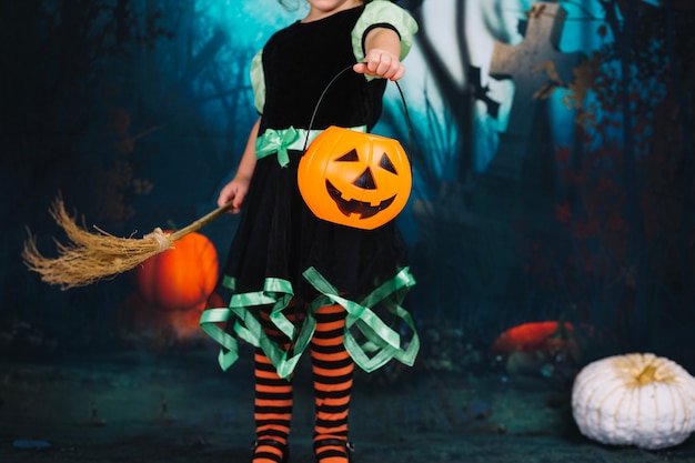 Free photo little witch holding broom and basket