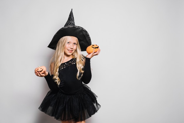 Little witch posing with jack-o-lanterns