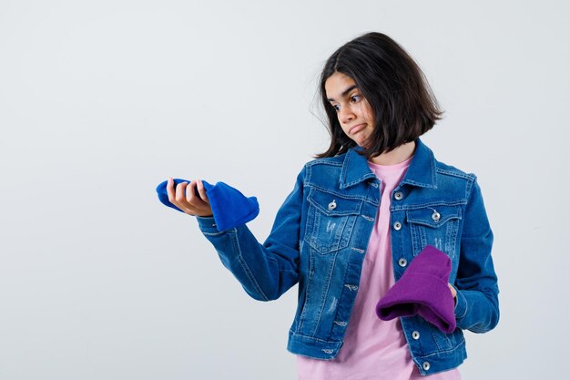 Free photo little woman looking at beanies in t-shirt denim jacket beanie looking indecisive