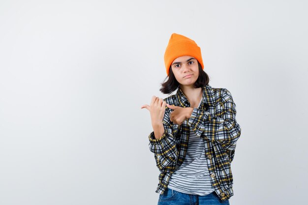 Little woman in t-shirt and jacket pointing thumb ups to the right side