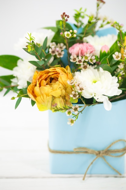 live spring flowers on a white in a blue pot with bow