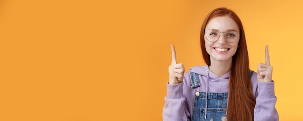 Free photo lively charismatic pleasant redhead female student helpful pointing up index fingers showing awesome