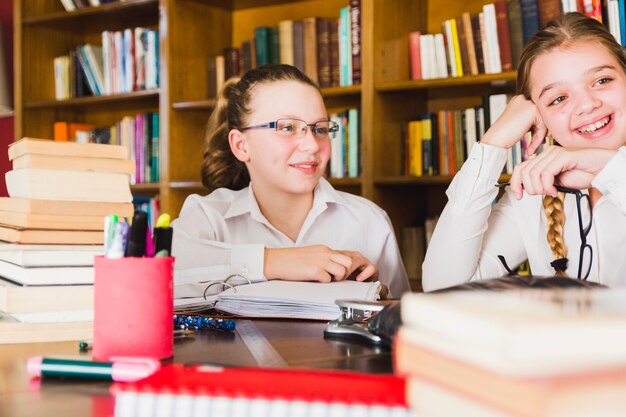 Free photo lively little girls sitting at library desk