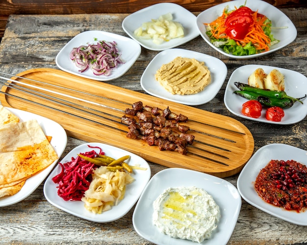 Foto gratuita hummus di kebab del fegato sottaceti la vista laterale del lavash della cipolla del pomodoro del pepe dell'insalata verde