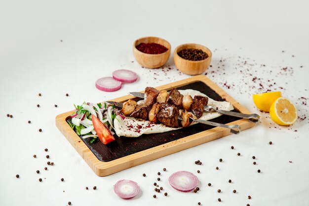 Liver kebab with fat and onions on a wooden board