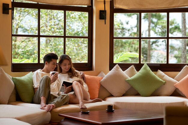  living room with panoramic windows and romantic couple sitting on large couch reading a book together