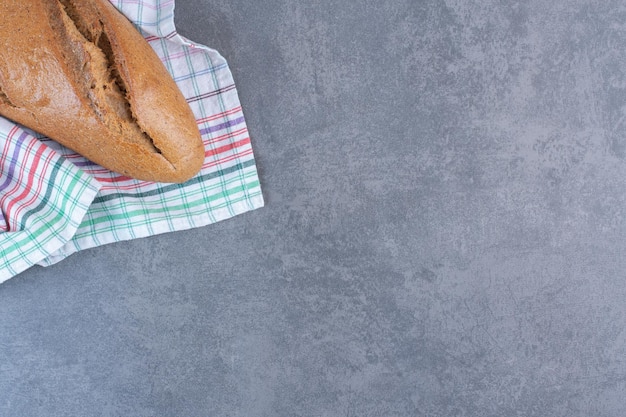 Loaf of baton bread on a towel on marble background. High quality photo