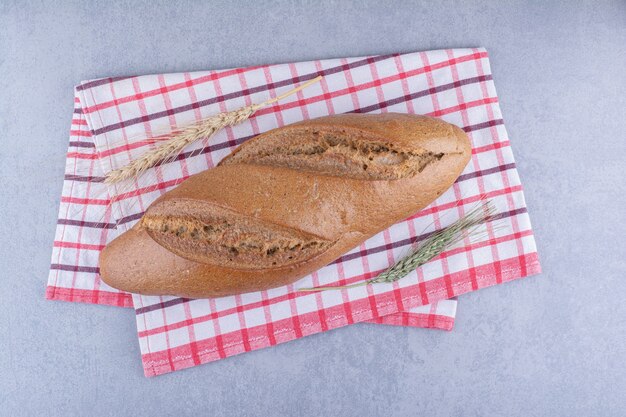 Loaf of baton bread on a towel on marble surface