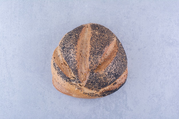 Loaf of black sesame coated bread on marble surface