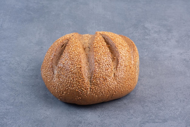 Loaf of bread covered in sesame seeds on marble background. High quality photo