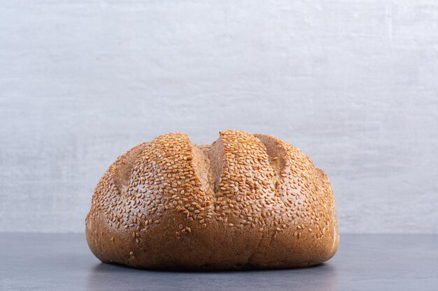 大理石の背景にゴマで覆われた一斤のパン。高品質の写真