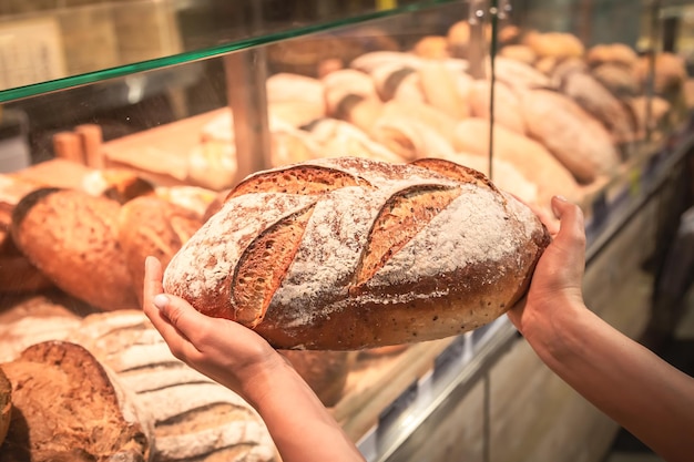 Free photo loaf of bread in female hands in a supermarket