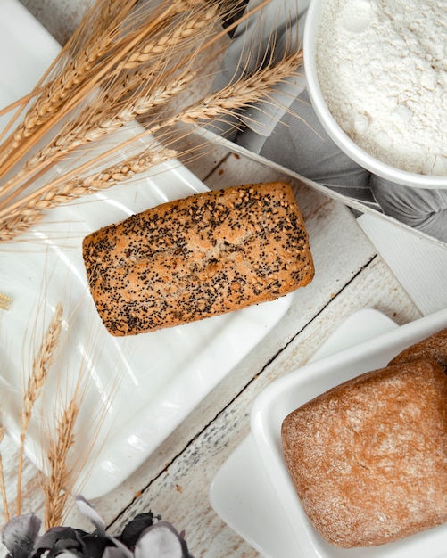 Free photo loaf of bread topped with poppy and wheat branches