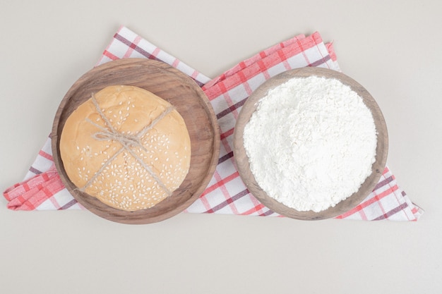 Loaf a burger bread in rope with flour on wooden plate