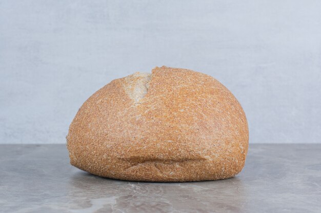 Loaf of fresh bread on marble background.