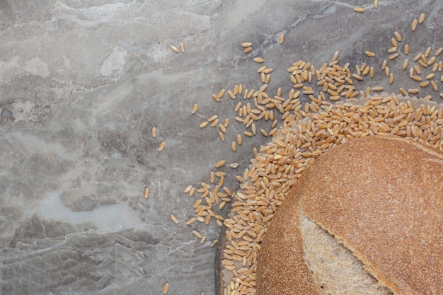 Foto gratuita pagnotta di pane fresco con chicchi di avena sulla superficie in marmo