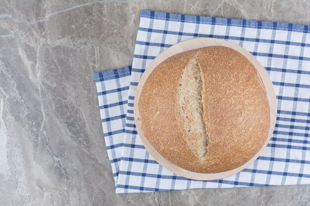 Loaf of fresh brown bread on tablecloth