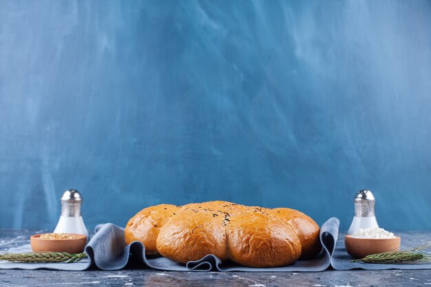 Буханка свежего ароматного хлеба с солью и перцем на синем.