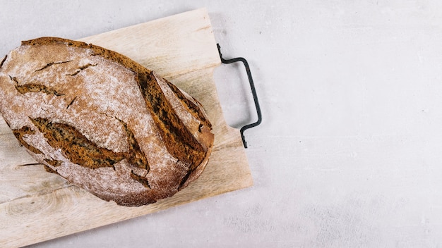 Free photo loaf of rustic baked bread on chopping board over white background