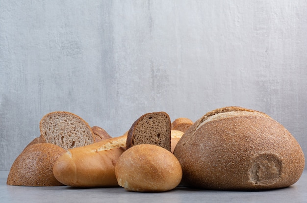 Free photo loaf and slices of bread on marble background. high quality photo