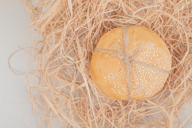 Loaf of small burger bread in rope on white surface