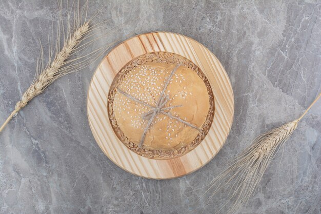 A loaf of white bread with oat grain on wooden board