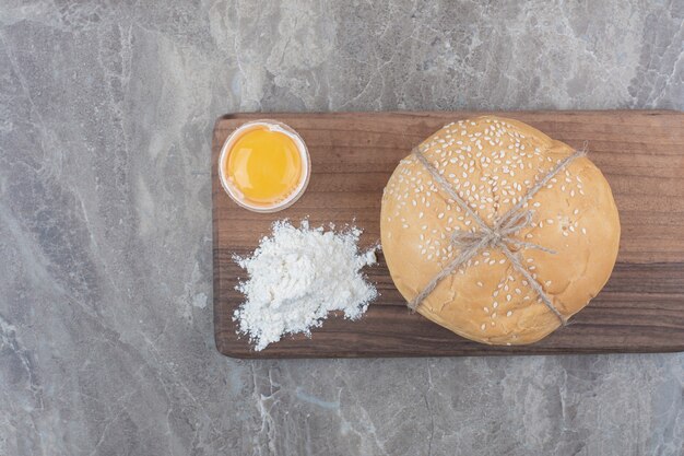 Free photo a loaf of white bread with yolk and flour on wooden board