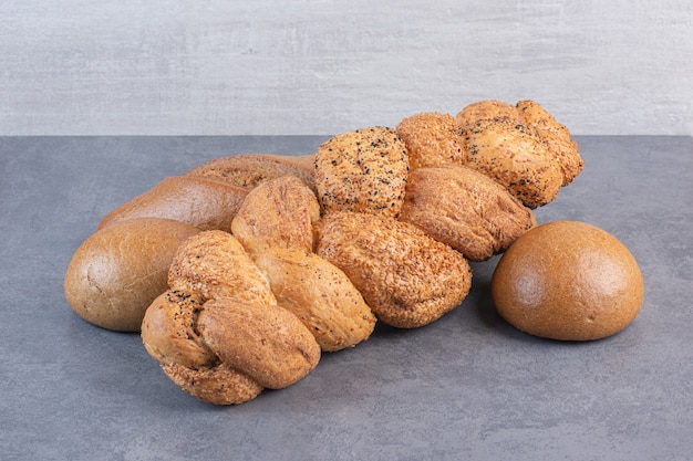 Free photo loaves of baton strucia and bun bread bundled on marble.