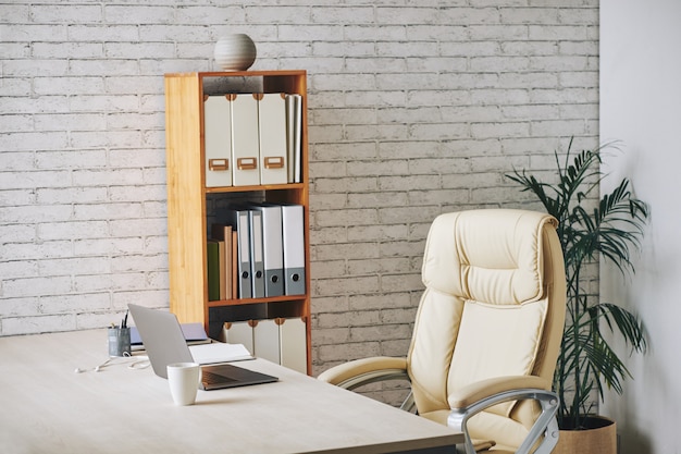 선반에 책상, 임원 의자 및 문서 폴더에 앉아 노트북과 로프트 스타일의 사무실