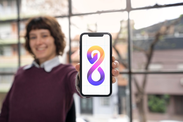 Free photo logo designer holding a smartphone with a cool logo on it