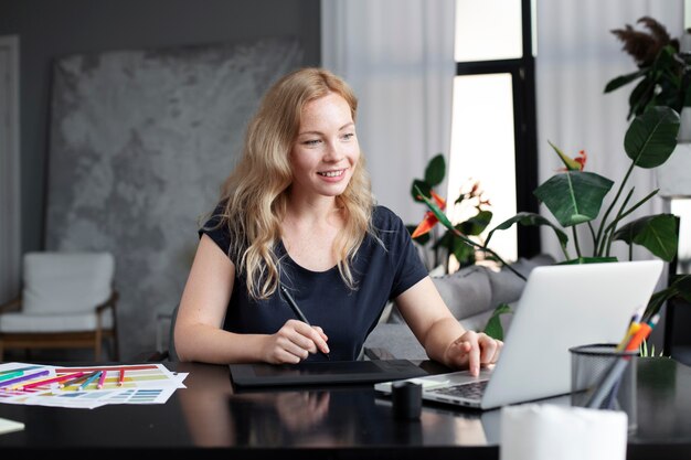 Logo designer working on her tablet connected to a laptop