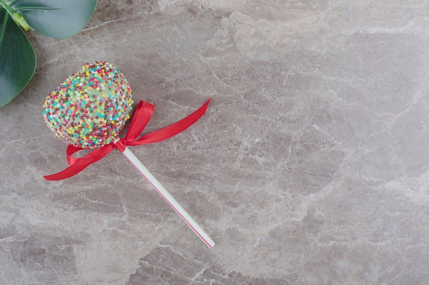 Free photo a lollipop and a decorative leaf on marble
