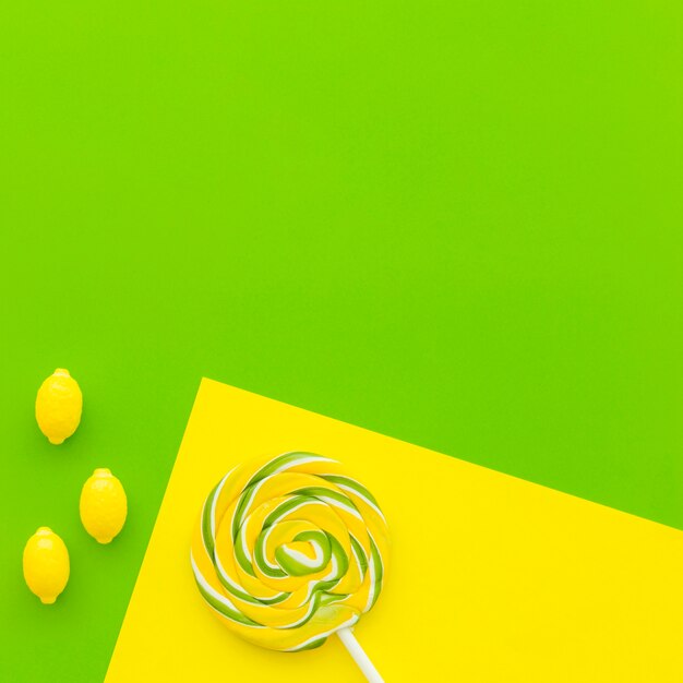 Lollipop and lemon candies on dual yellow and green background