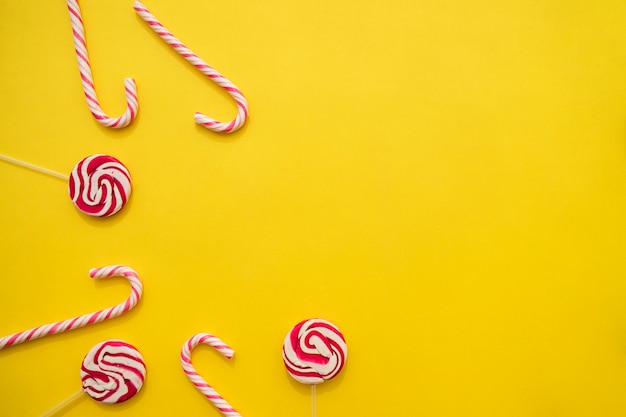 Lollipops and candy canes on yellow background