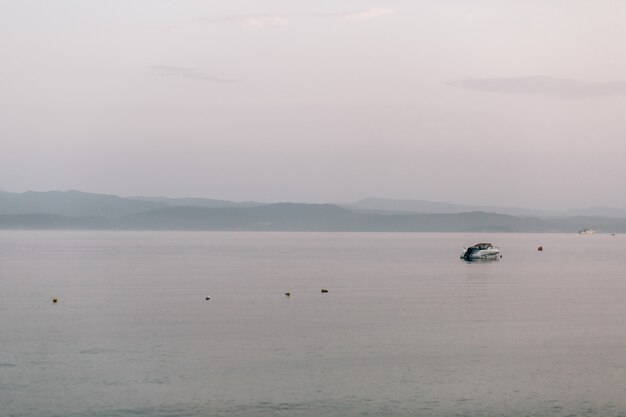 Lonely boat floats in the sea under grey sky