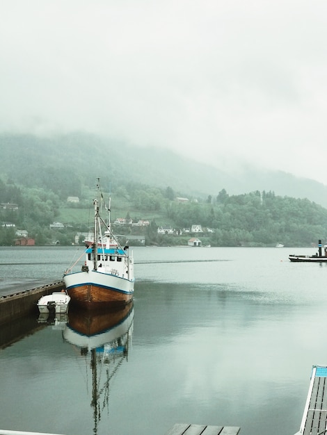 Lonely boat stands on the pierce covered with fog