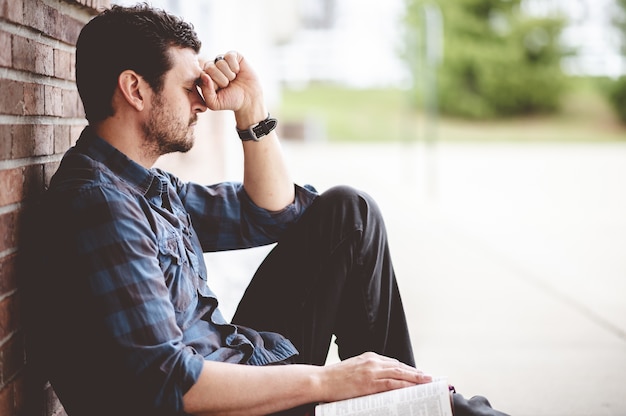 Lonely depressed person sitting near a brick wall