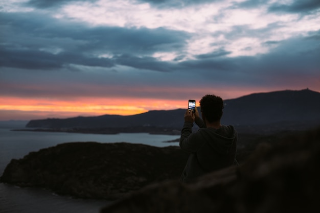 Lonely figure of tourist or traveler that stands on top of cliff or mountain