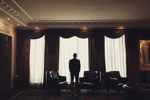 Lonely man stands before the window in a room