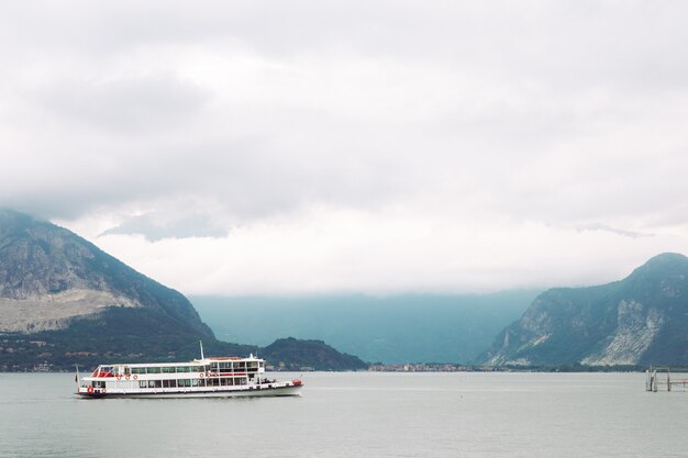 Lonely white boat stands on the sea before the mountains