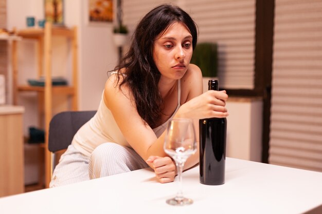 Lonely woman holding a bottle of red wine