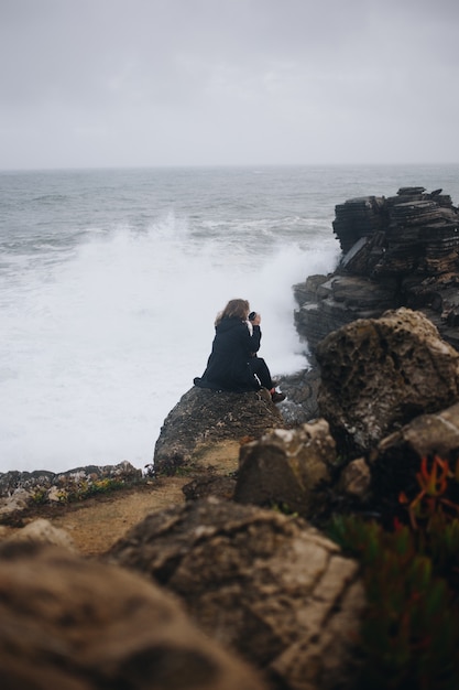 Lonely woman sit on cliff in rain storm
