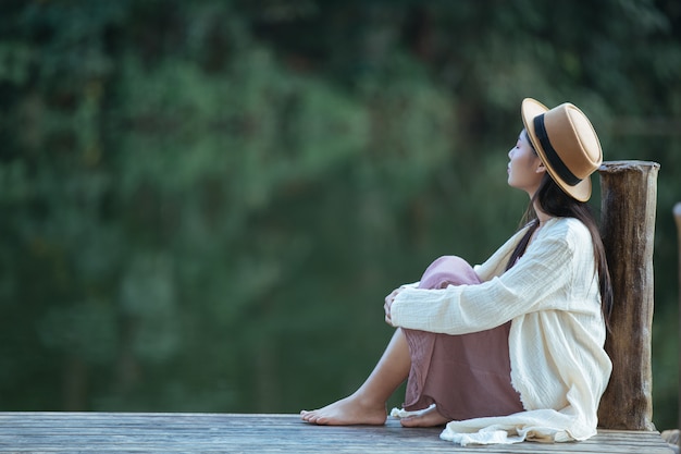 Одинокая женщина, сидящая на плоту на набережной