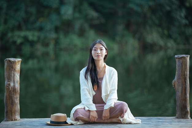 Free photo lonely woman sitting on the waterfront raft