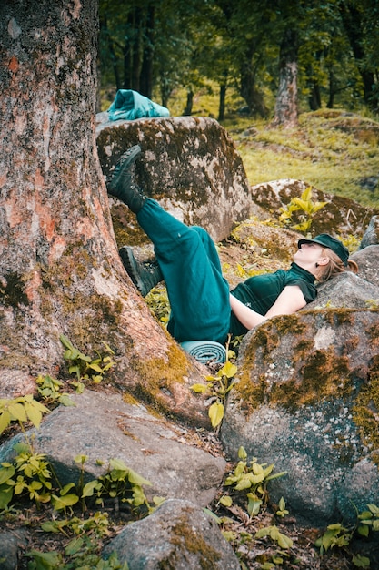 나무와 암석 옆에서 자고 있는 외로운 젊은 여성