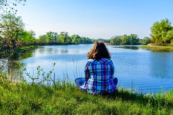 Одинокая молодая женщина, сидящая на берегу реки